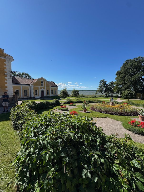 Formal garden with curved hedges and flower beds in front of the manor buildings at Julita Gård