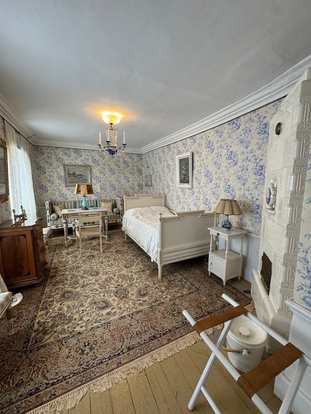 Bedroom in Julita manor with blue and white wallpaper, a white bed and a large rug