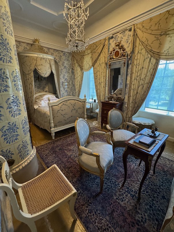 Bedroom in Julita manor with a canopy bed, yellow curtains and light painted chairs