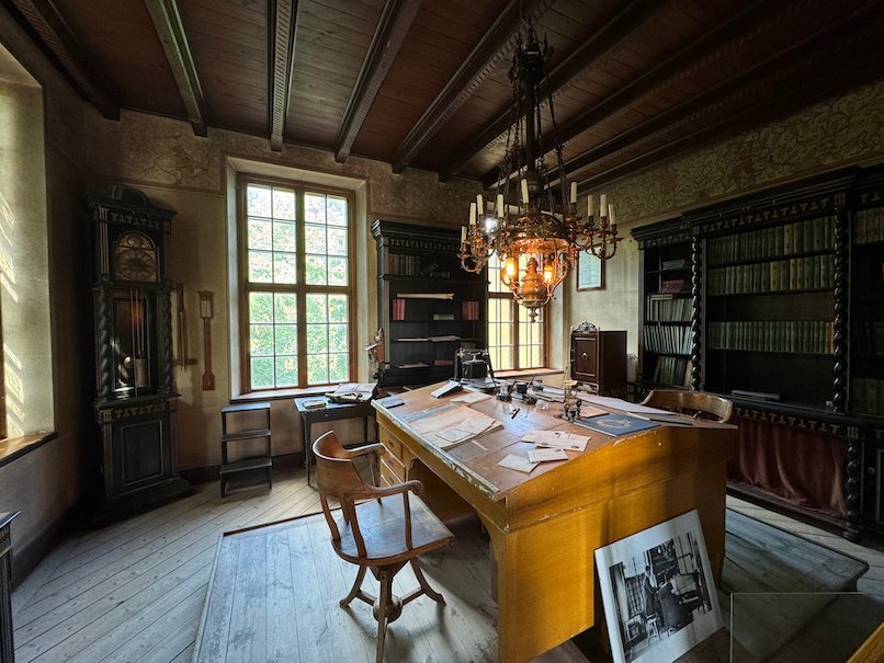 Library room in Julita manor with bookcases, a large wooden desk and a brass chandelier