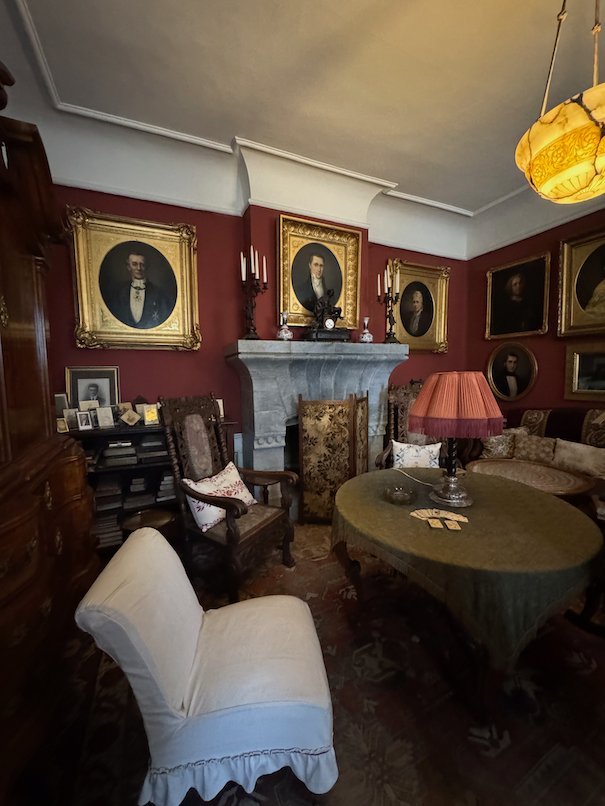 Room with dark red walls in Julita manor, with family portraits, a fireplace and armchairs
