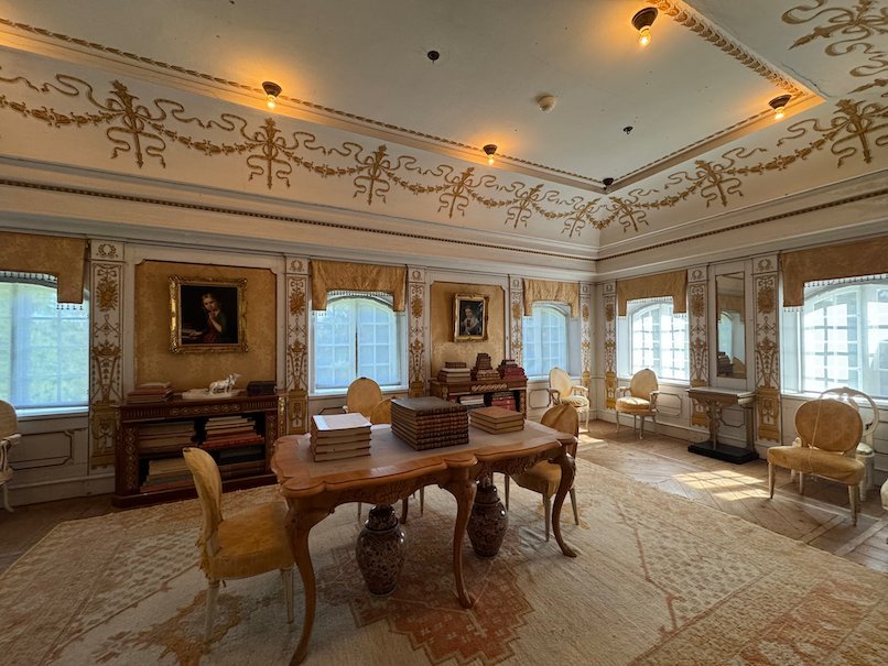Room in Julita manor with a painted ceiling border, portraits on the walls and a writing desk