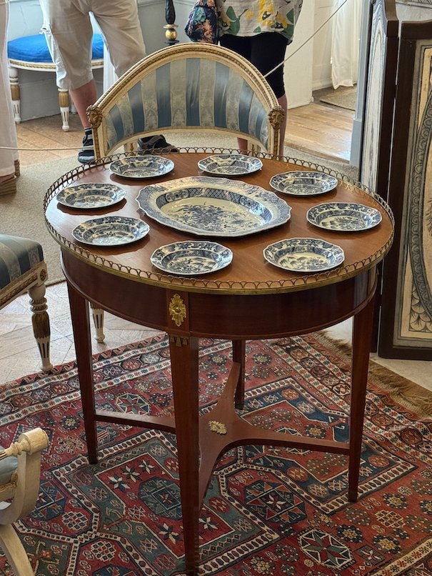 Round wooden table with blue and white plates on display, in a room in Julita manor