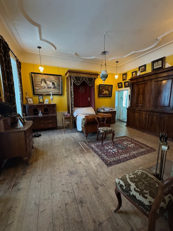 Room with yellow walls in Julita manor, with a bed in an alcove and wooden furniture