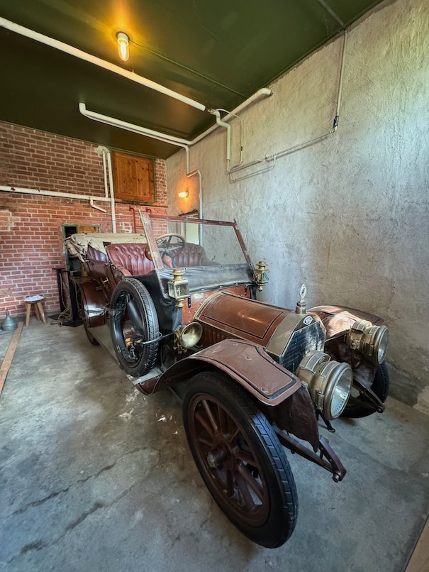 Brown Opel car from 1908 with large spoked wheels, inside an old garage at Julita Gård