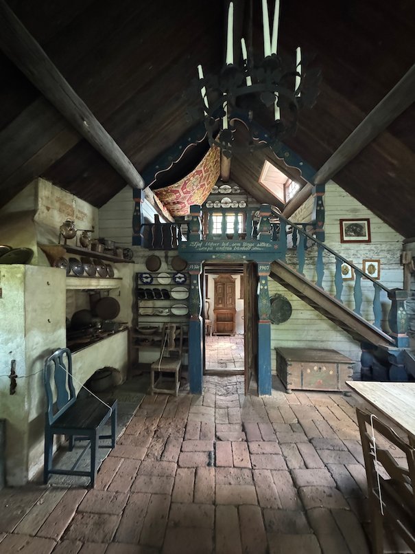 Interior of Smedjestugan with a wooden floor, a painted wooden staircase and old household objects