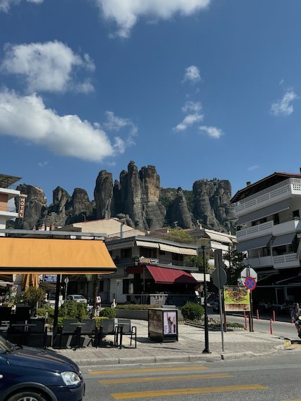 Street with cafés in Kalambaka with the rock towers of Meteora behind