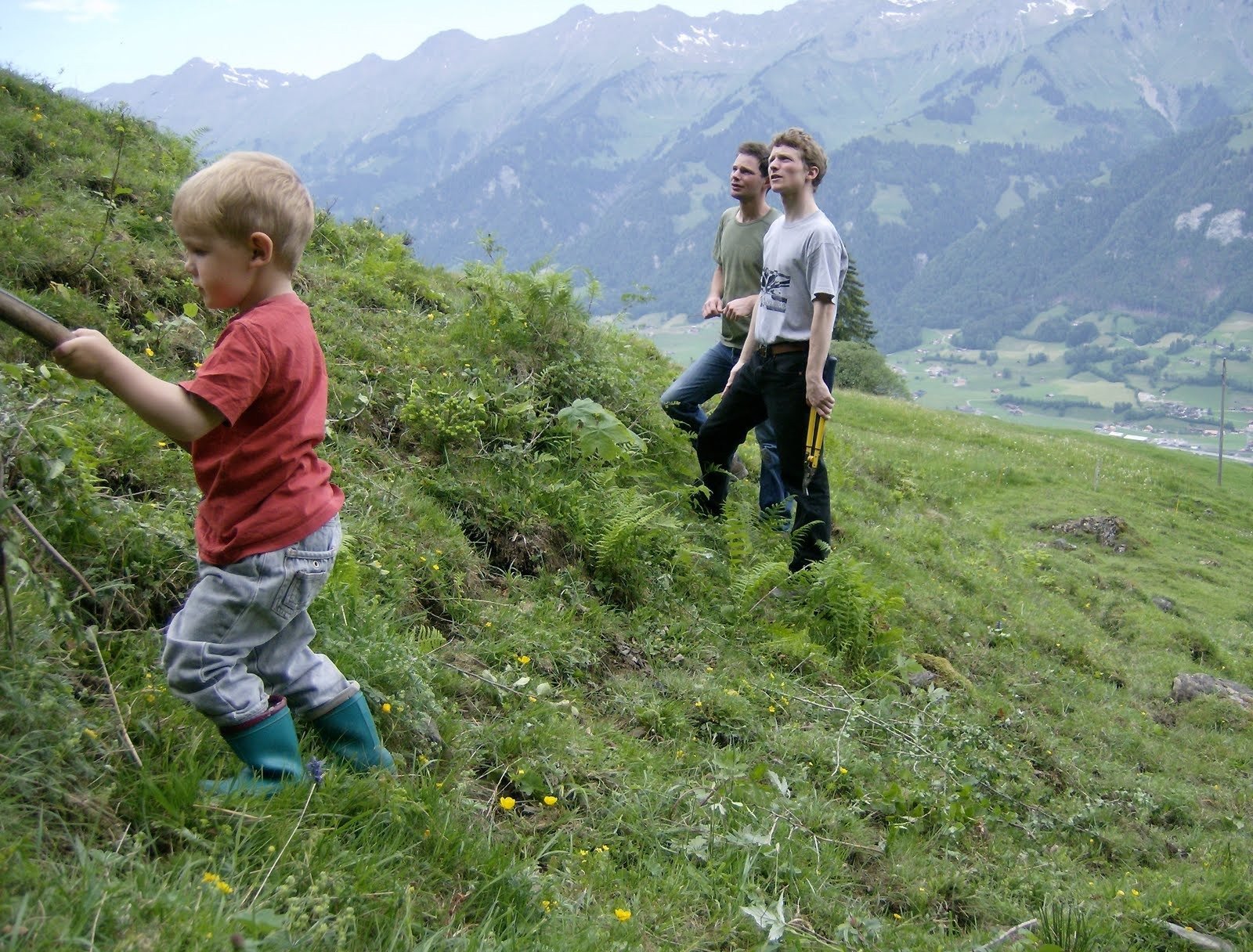 A child walks up a steep alpine slope with mountains behind in Switzerland.