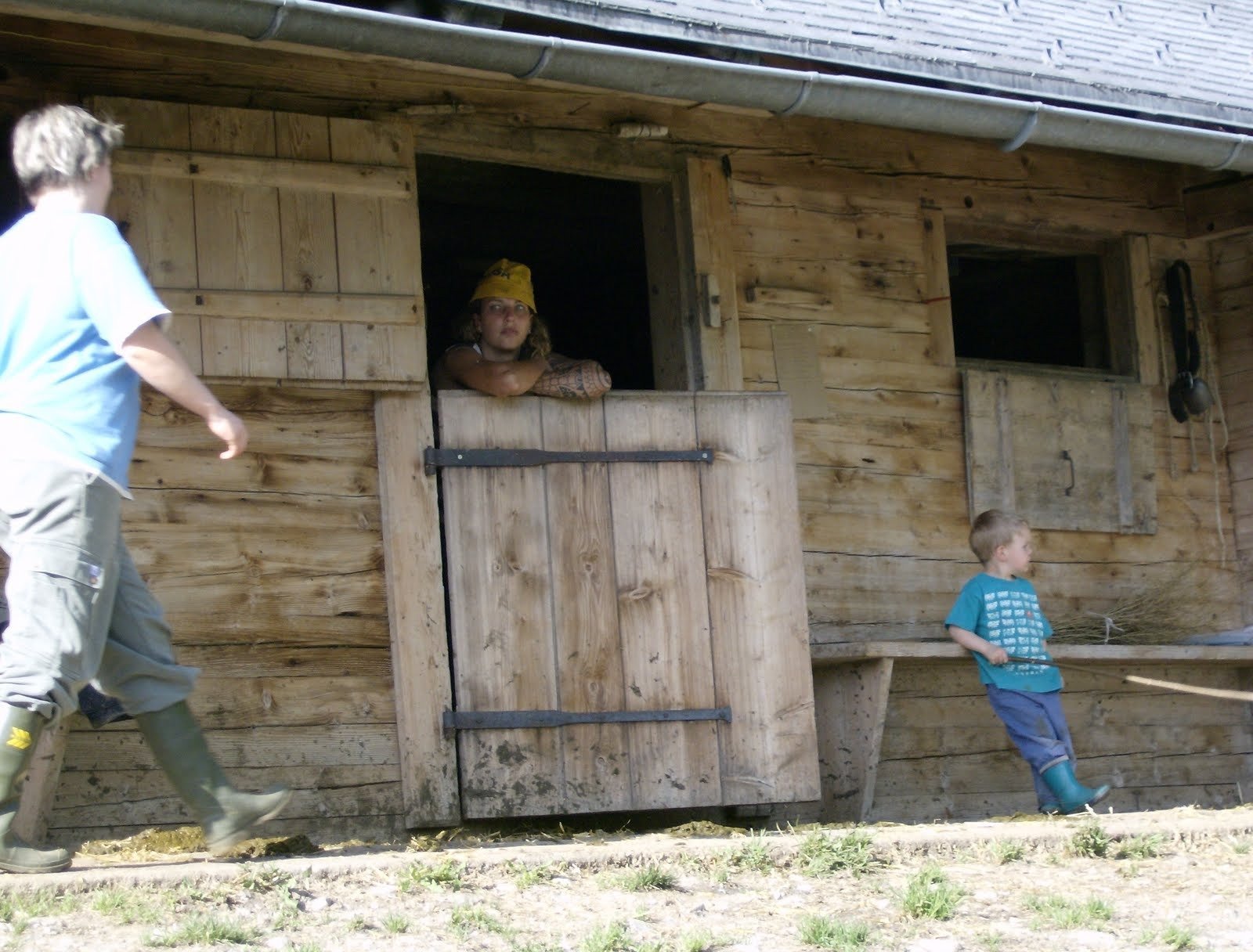 People and a child stand at the wooden stable doors of an alp farm.