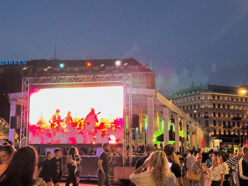 Festival crowd in front of a big screen with a live concert at night in central Stockholm