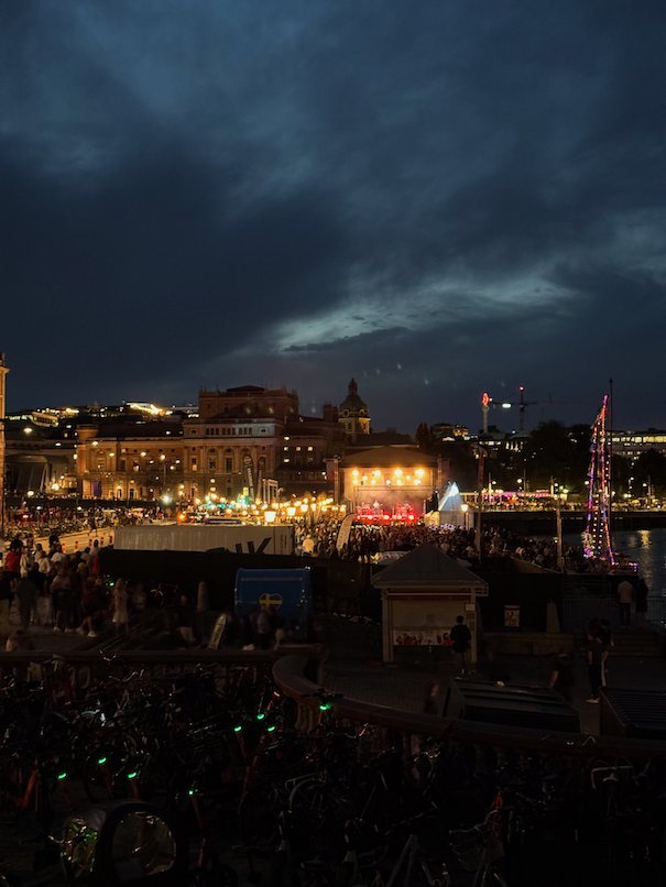 Stockholm at dusk during Kulturfestivalen, with festival lights by the water under dark clouds