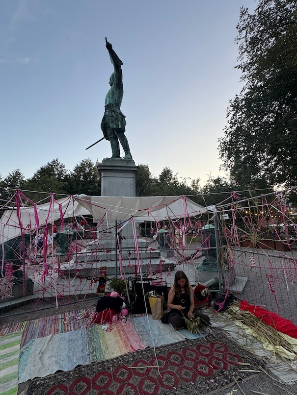 An art installation with colourful fabric and rugs around a bronze statue in a park during Kulturfestivalen