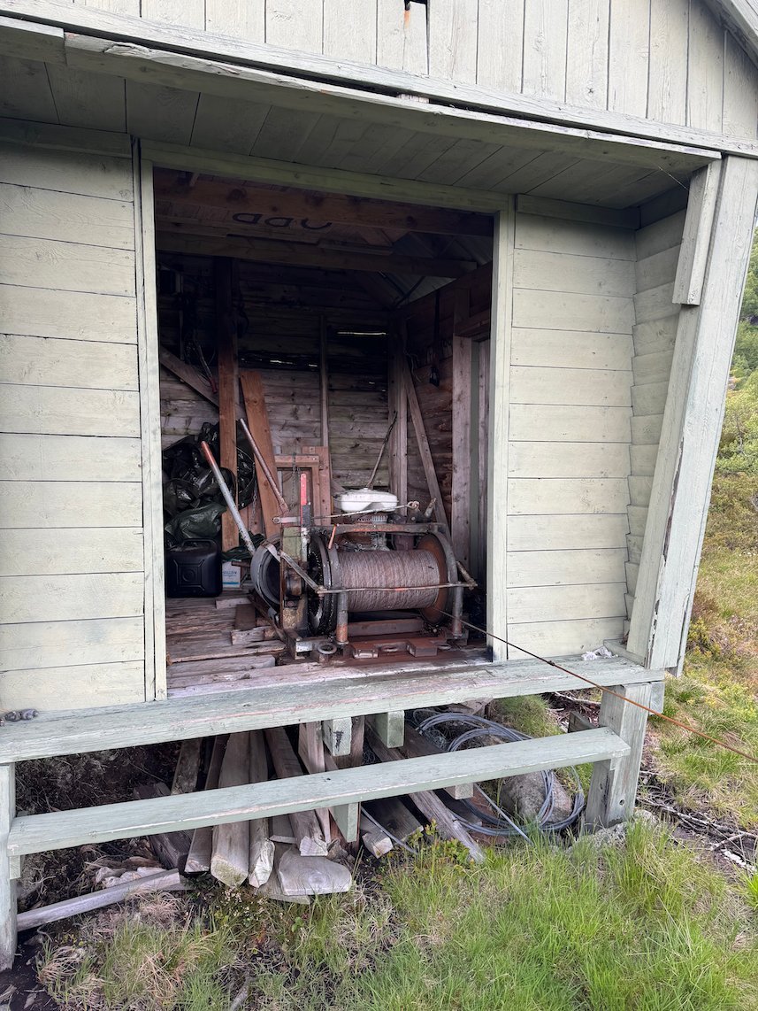 Old farm machine inside an open white shed on the mountain