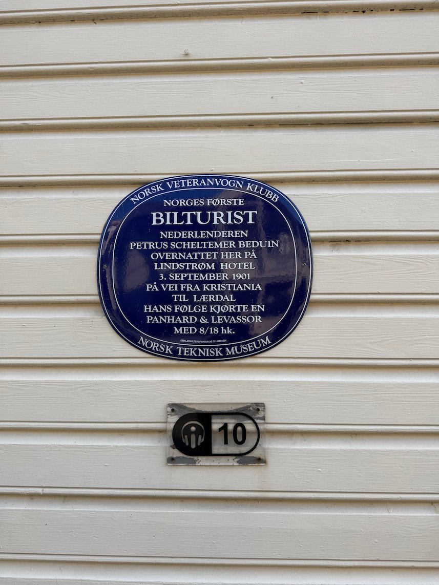 Blue plaque Bilturist on a white wooden house in Lærdal, about the first motor tourist in Norway
