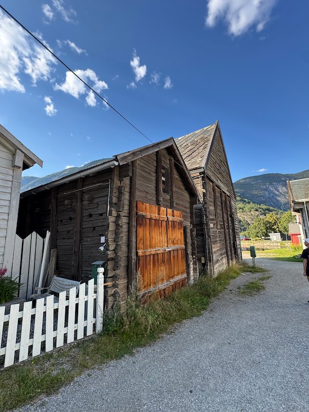Old dark wooden barn and a white picket fence in Lærdalsøyri
