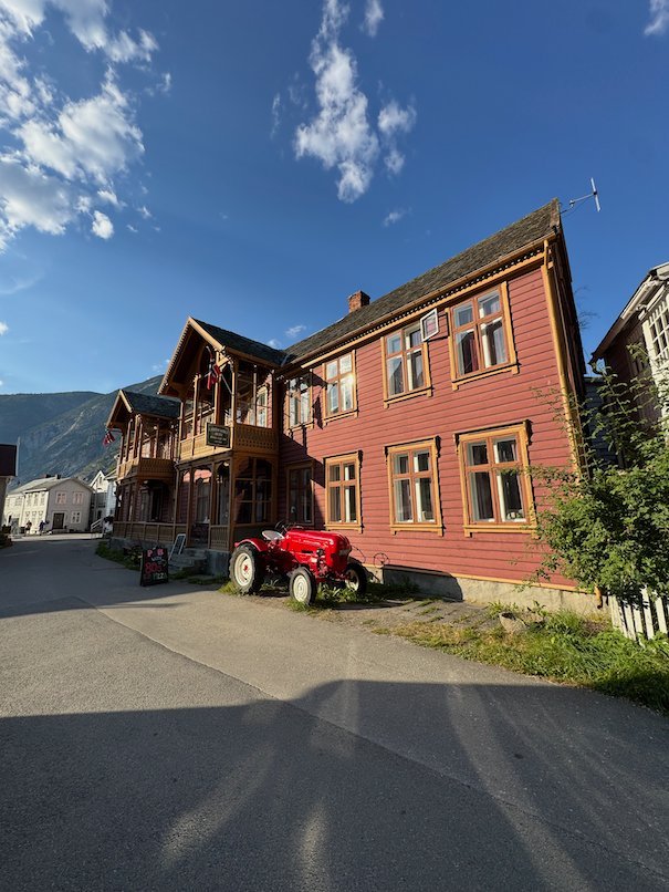 Red wooden house with a red tractor in front, in old Lærdalsøyri