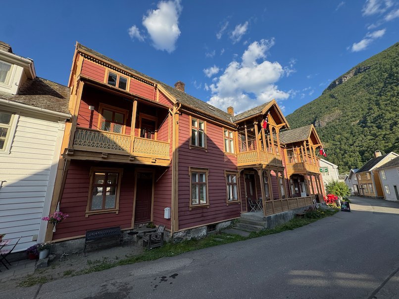 Red wooden houses with balconies below steep mountains in Lærdalsøyri