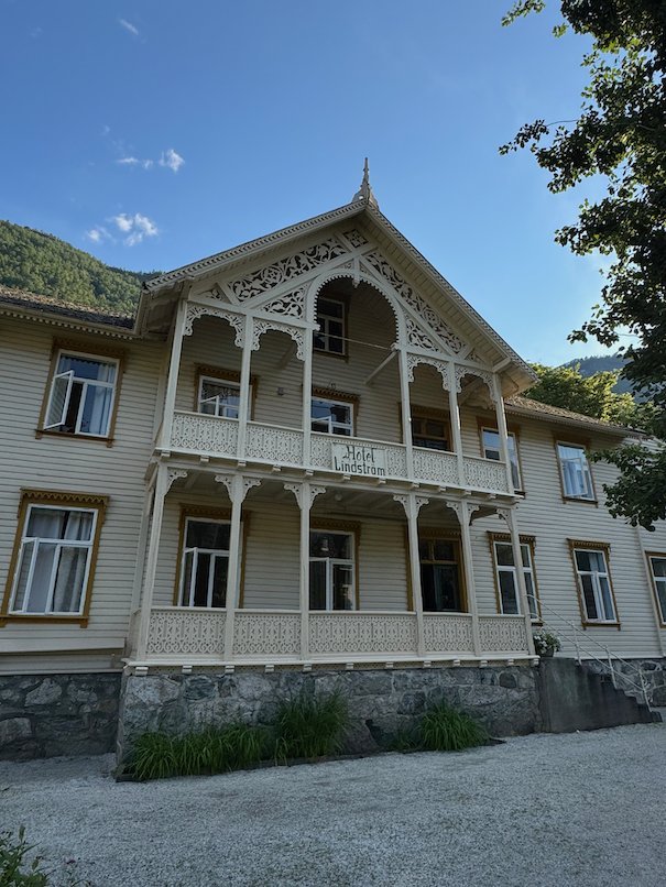 White wooden house with ornate verandas and a stone base in old Lærdalsøyri