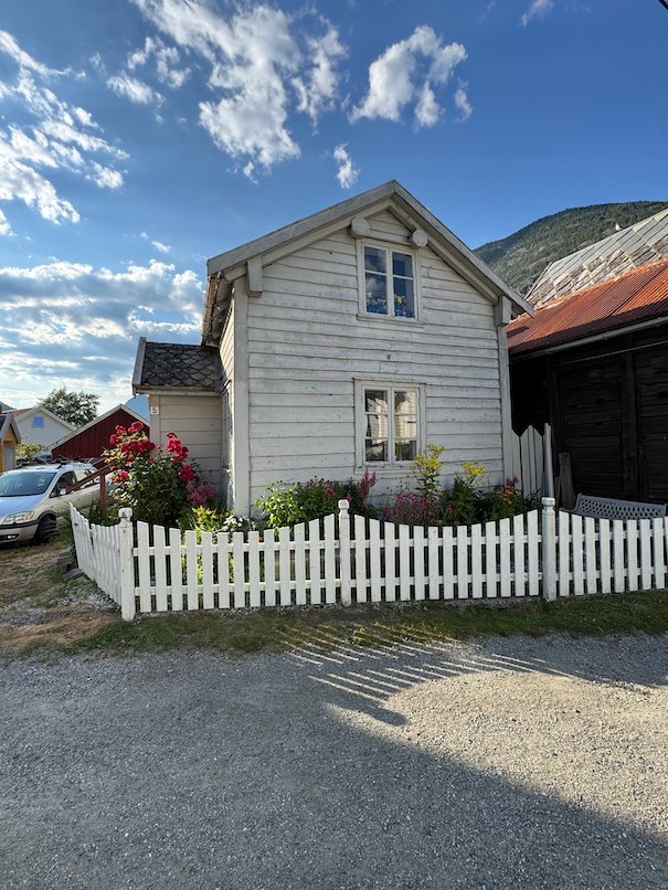 White wooden house with roses and a picket fence in Lærdalsøyri