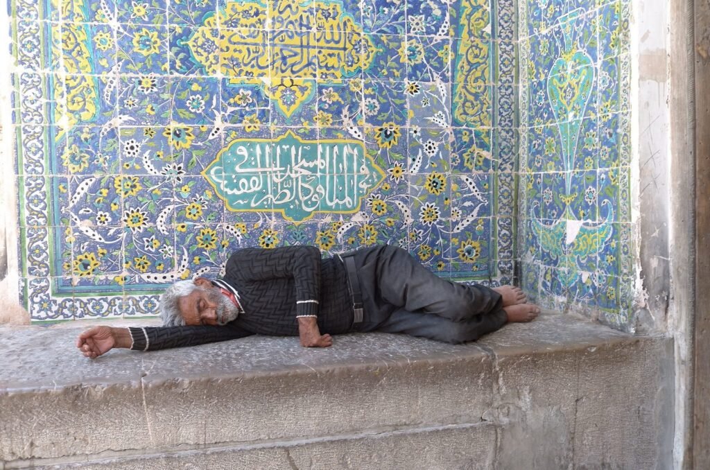 Man who rests on a bench by a tiled wall in Isfahan