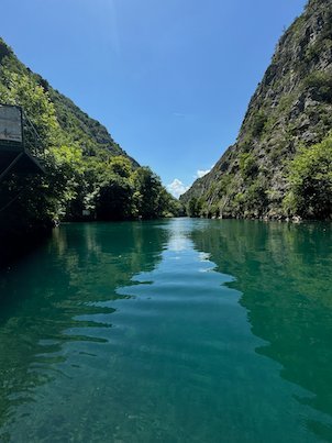 Steep green cliffs reflect in the calm river in Matka Canyon near Skopje.