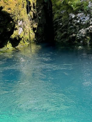 Clear blue water flows past a mossy rock wall in Matka Canyon near Skopje.