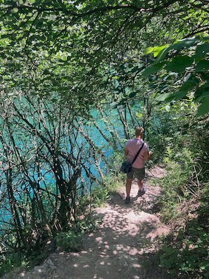 A traveler walks on a path above the turquoise water at Matka Canyon.