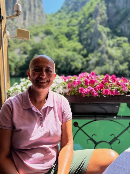 Zayera Khan smiles at a restaurant table with pink flowers and the canyon behind her at Matka.