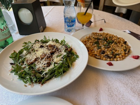 A rocket salad and a plate of beans sit on a white tablecloth at a restaurant at Matka.