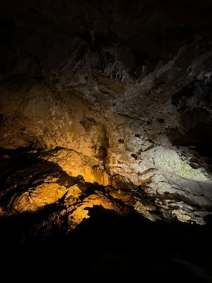 Orange light shows a rock mound in a dark chamber of Vrelo Cave at Matka.