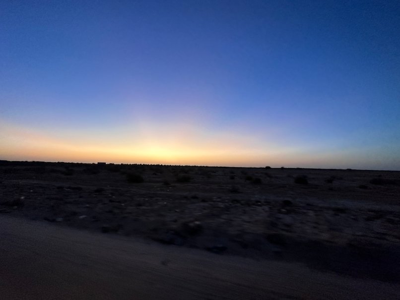 The last light of dusk glows over the dark desert.