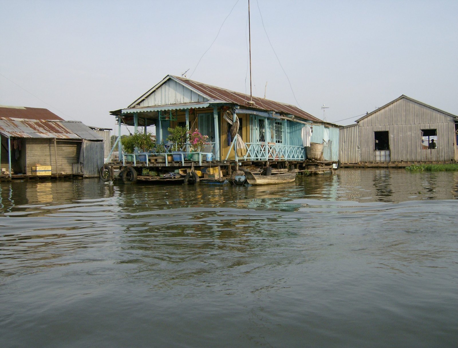 Colorful floating houses lie on calm water on a river in the Mekong Delta.