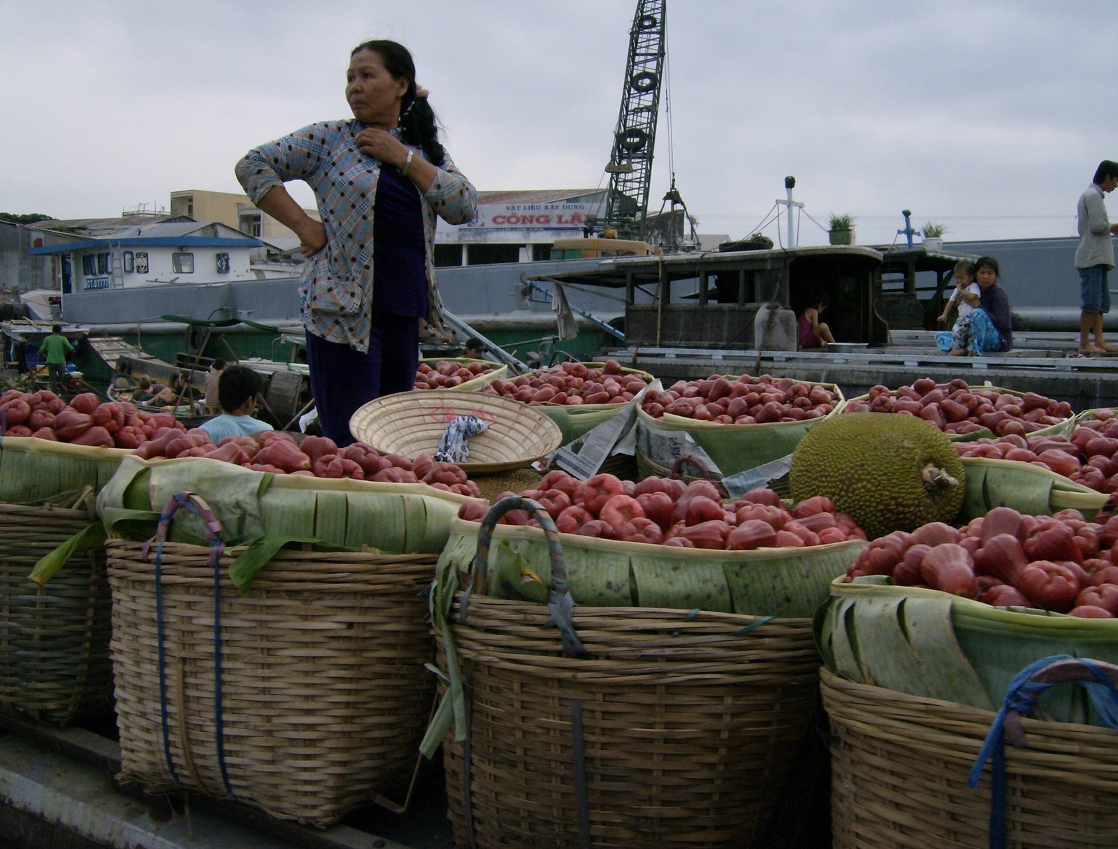 A woman stands on a boat full of fruit baskets at a floating market in the Mekong Delta.