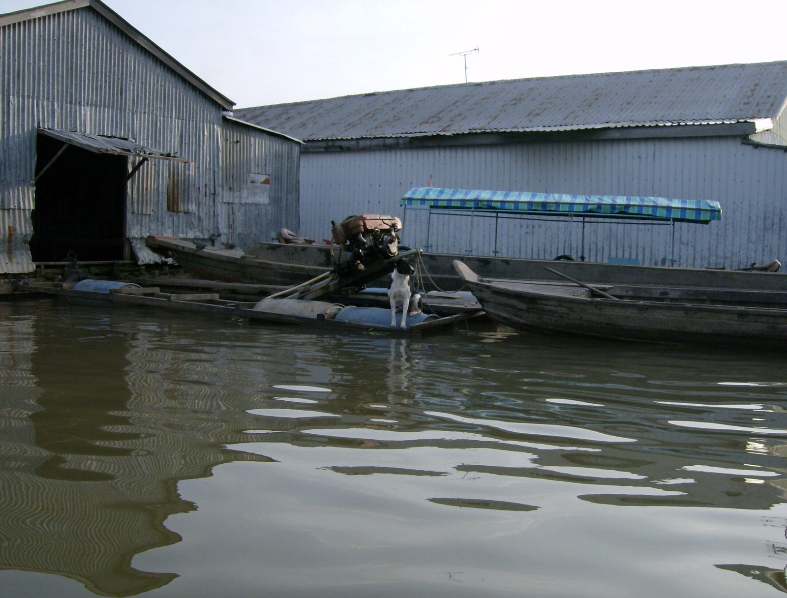 Boats lie next to large tin floating sheds on the river in the Mekong Delta.