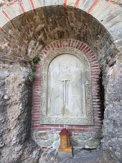 Carved stone relief in a brick niche, with a small candle box below