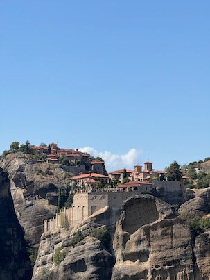 Monastery with red roofs built on top of a high rock at Meteora