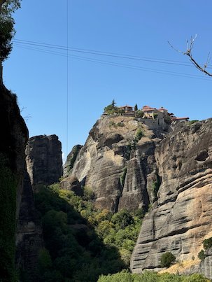Monastery on top of a high cliff above a green gorge at Meteora
