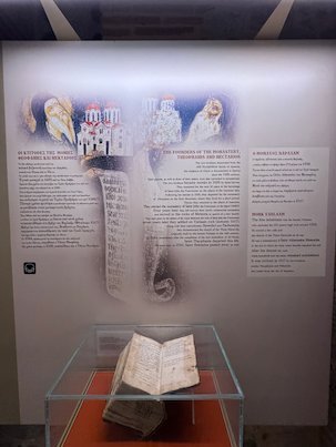 Old book in a glass case under a wall panel in a Meteora monastery museum