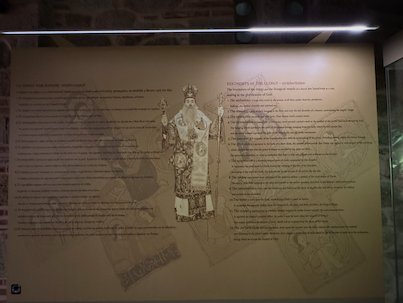 Museum wall panel with text and a drawing of a bishop in a Meteora monastery