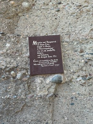 Plaque with a prayer in Greek and English on the rock wall at Meteora