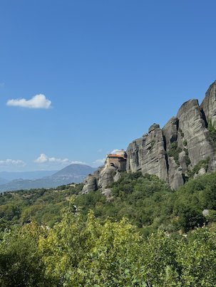 Rock ridge with a small monastery above green hills at Meteora