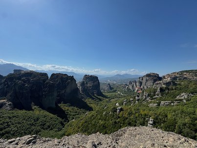 Rock towers of Meteora above a green valley under a blue sky