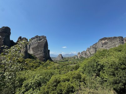 Rock towers and green bushes at Meteora under a blue sky