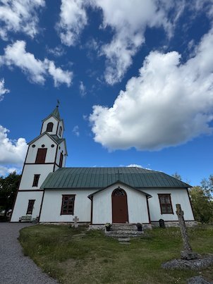 Front of Möja church, a white wooden church with a green roof and a gravel path