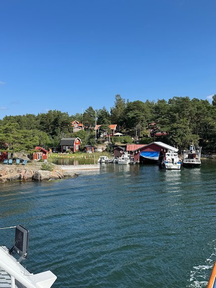Harbour with red boathouses and boats, seen from the deck of a ferry