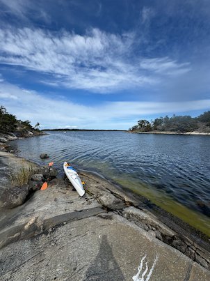 White kayak pulled up on a flat rock at the water edge