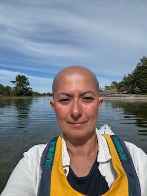 Selfie in a yellow life jacket on a calm bay with a wooded shore