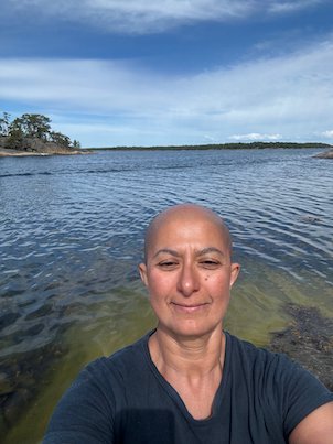 Selfie in a kayak above clear shallow water, with islands and blue sky behind