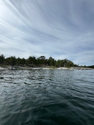Low island with bare rocks under streaky white clouds