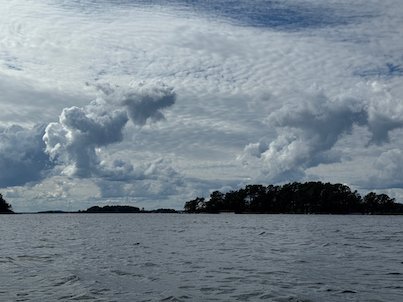 Dark island silhouettes under large grey clouds over the water